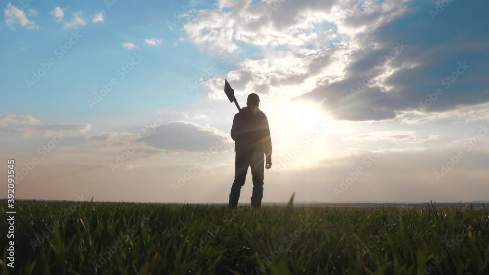 man farmer silhouette red neck holding a shovel in his hand walking across the field a lifestyle pile of dirt soil. Eco smart agriculture land farming concept. worker agronomist with a shovel goes to man farmer silhouette red neck holding a shovel in his hand walking across the field a lifestyle pile of dirt soil. Eco smart agriculture land farming concept. worker agronomist with a shovel goes to