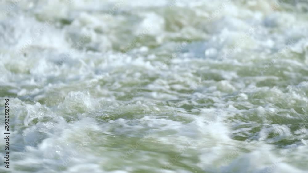 Closeup detail, water flowing in river on sunny day forming white waves Closeup detail, water flowing in river on sunny day forming white waves