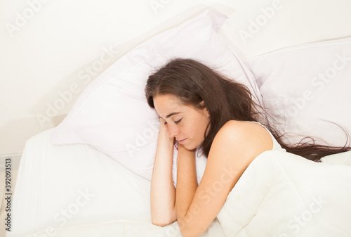 Portrait of a young attractive woman with long hair sleeping in her bed