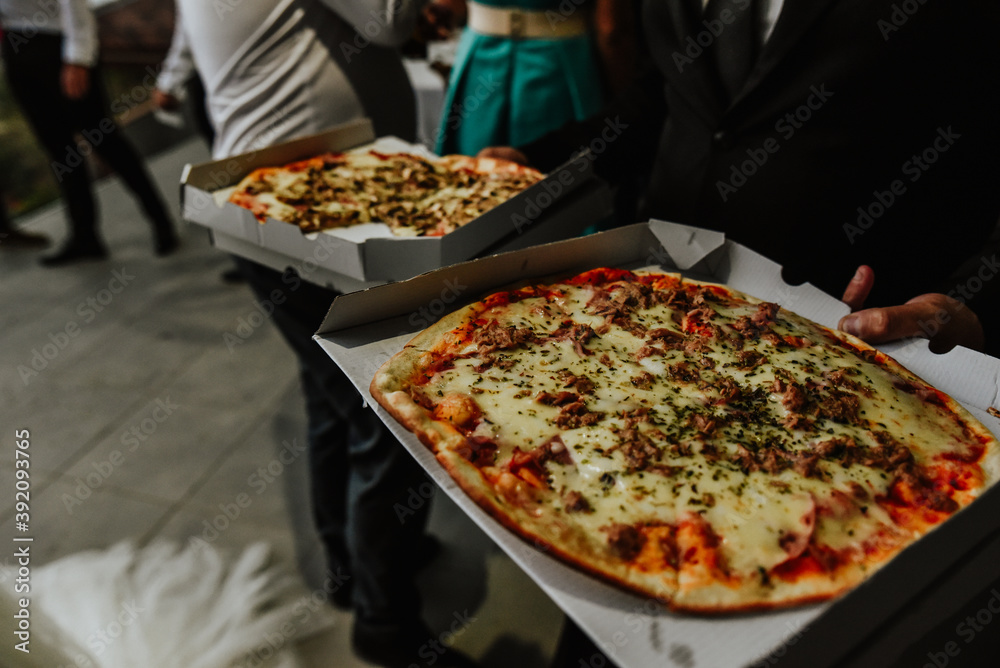 close up of pizza. Waiter handing out pizzas to guests at an evening event