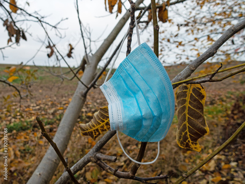 Mundschutzmaske am Baum hängend im Herbst