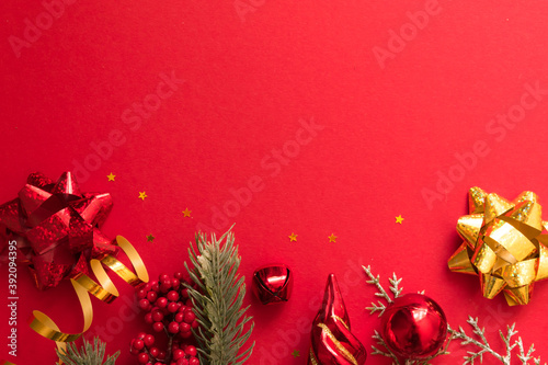Beautiful Christmas composition with gift box tied with a ribbon, presents and fir branches on red background.