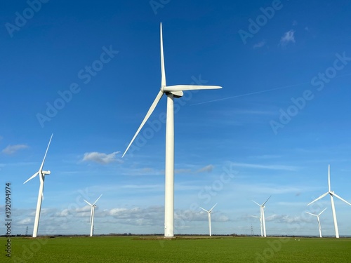 Wind turbines that produce electricity energy. Windmill Wind power technology productions Wind turbines standing on a blooming fields in green field. 