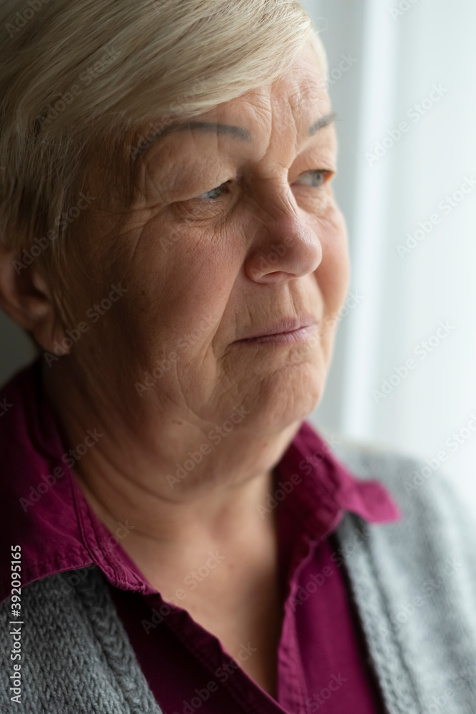 Face of an elderly woman looking out the window. Close-up portrait of old sad woman. Face of an elderly woman looking out the window. Close-up portrait of old sad woman.