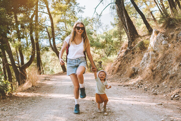 Mother with child daughter walking in forest family vacation mom travel with baby hiking together active healthy lifestyle outdoor happy emotions