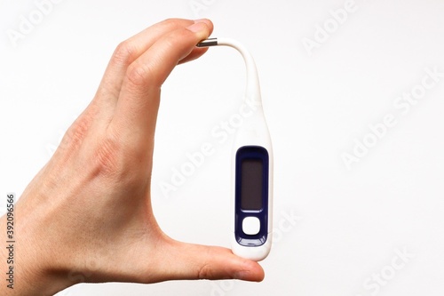 hand holding a digital thermometer. Hand bends thermometer on white background