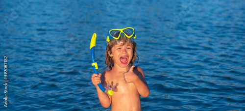 Happy kid boy wearing snorkel mask in sea or ocean show thumbs up, like ok.