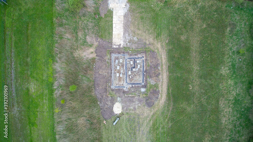 Top down view on detached house under construction. House in basic state. Located on green plot in small village. Meadows around.