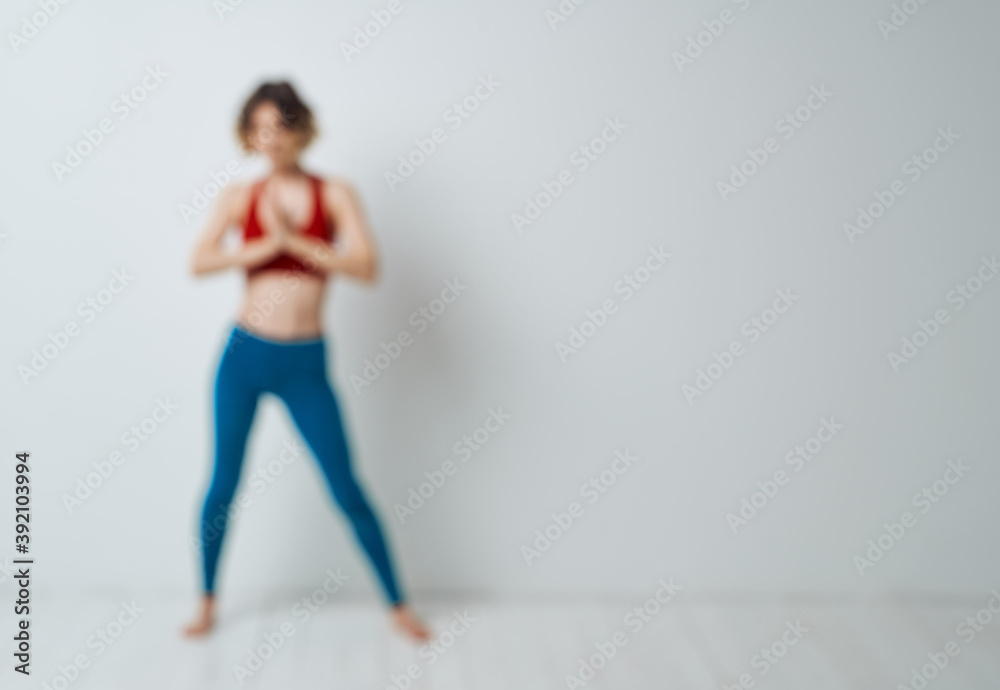 Obraz premium woman doing yoga in a bright room and blue leggings red tank top