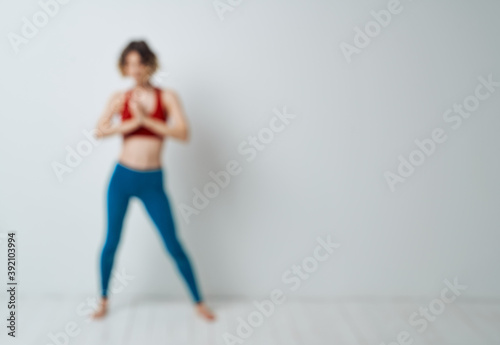 woman doing yoga in a bright room and blue leggings red tank top