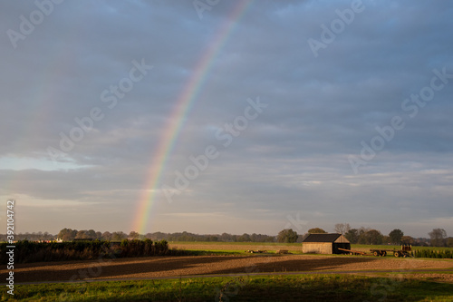 Rainbow over stormy sky. Rural landscape with rainbow over dark stormy sky in a countryside at autumn day