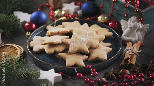 Powdered sugar falls on Christmas cookies. Gingerbread cookies in a plate and New Year's gifts around, rotate on their axis. Christmas sweets background.