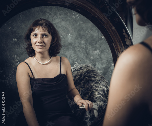 Cheerful 40 years old woman in classic dress watching at the retro style mirror © idea_studio