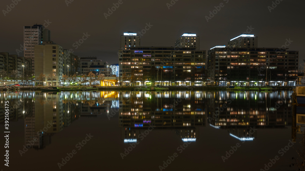 A beautiful night cityscape of a modern residential district casting reflection on the calm river.
