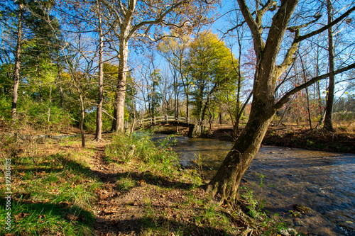 A Wooden Bridge Going Over a Small Stream on a Clear Autumn Day