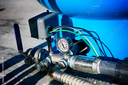 Deep water well set up. Water pressure gauge and storage tank.