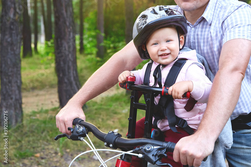 Close-up baby in a bicycle seat on a bicycle with dad. Family and outdoor activities concept.