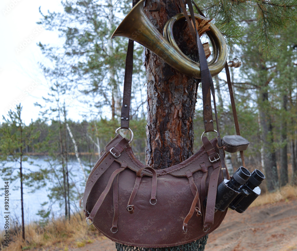 binoculars, old bag, hunting bugle hanging on a tree in the forest in autumn binoculars, old bag, hunting bugle hanging on a tree in the forest in autumn