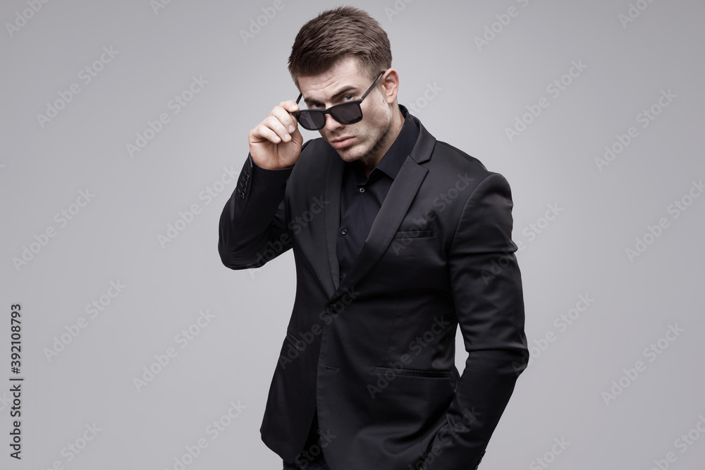 Portrait of beautyful smiling guy on gray background. High fashion model posing in studio. Attractive man in classic suit. Portrait of beautyful smiling guy on gray background. High fashion model posing in studio. Attractive man in classic suit.