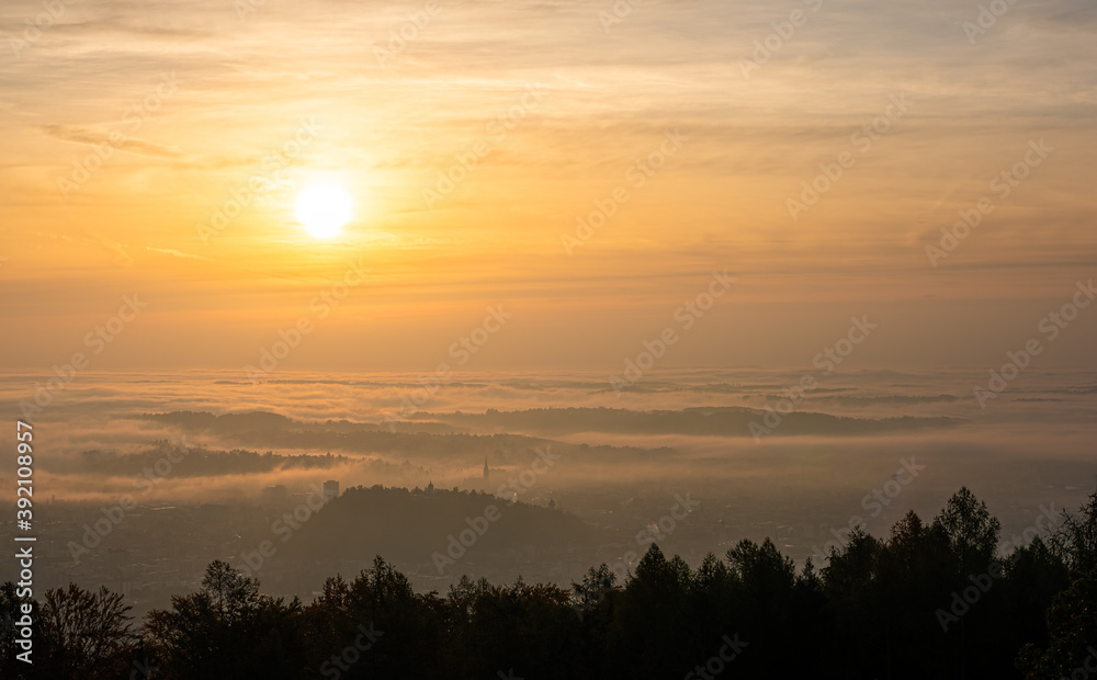 Panorama of Graz city in Styria on autumn morning during sunraise above fog