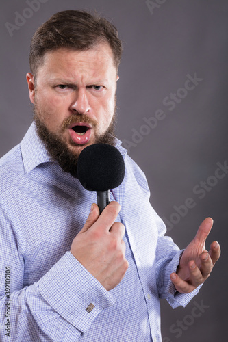 Bearded emotional singer with micriphone dressed in shirt photo