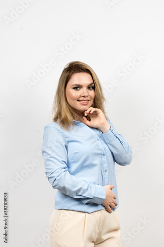 Photo of a woman on a light background. The woman holds her head with her hand. The body is slightly turned to the right. The woman looks straight and smiles. High quality photo.