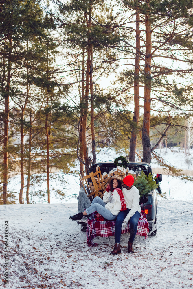 Happy multiracial couple in white sweatshirts during a trip to the forest for the christmas tree.
