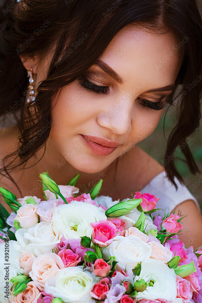 Portrait of merciful bride standing with wedding bouquet. Brunette at photoshoot in park Portrait of merciful bride standing with wedding bouquet. Brunette at photoshoot in park