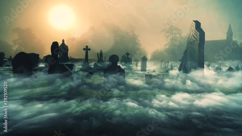 Spooky supernatural graveyard in the early morning with silhouette tombstone and fog.