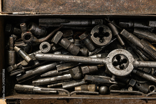 Old vintage iron toolbox full of drills and threading die tools as background