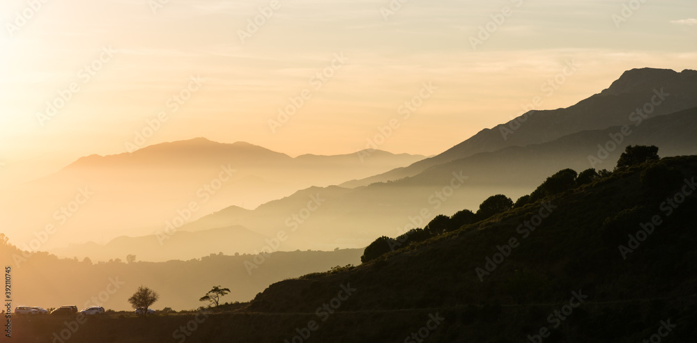 silhouettes of the mountains with two lonely trees at sunset.
Panoramic photo of the beautiful orange sunset from the top of the mountain in Marbella, Malaga, Andalucia, Spain.