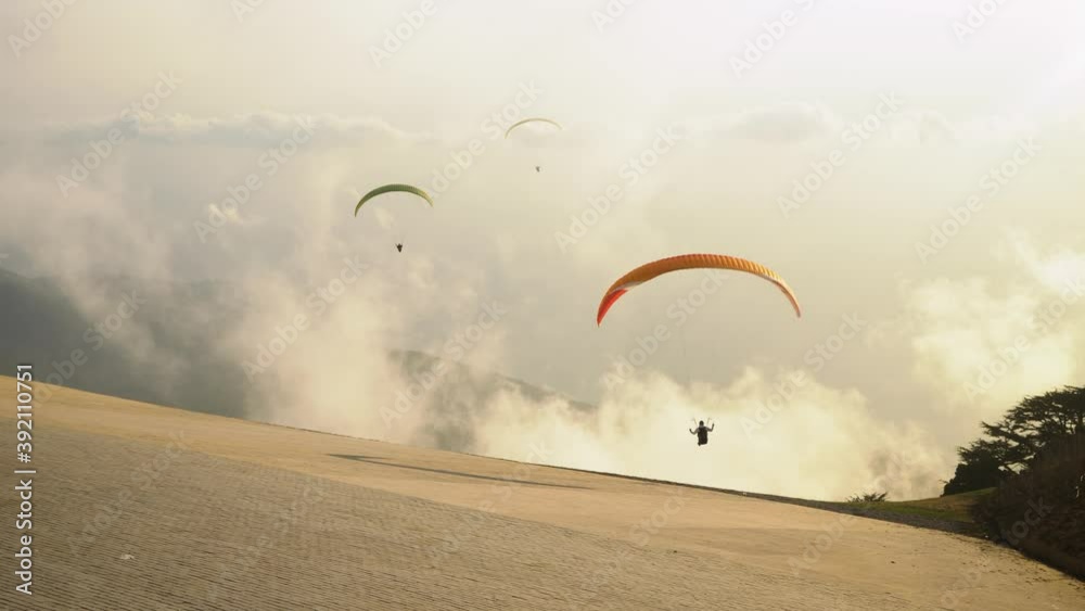 Paragliders prepareing to take off from a mountain. Paragliding in the sky at evening sunset in sea background. Extreme sport Paragliders prepareing to take off from a mountain. Paragliding in the sky at evening sunset in sea background. Extreme sport