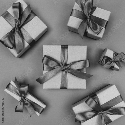 Gift boxes wrapped in craft paper with black ribbons and bows. Festive monochrome flat lay.