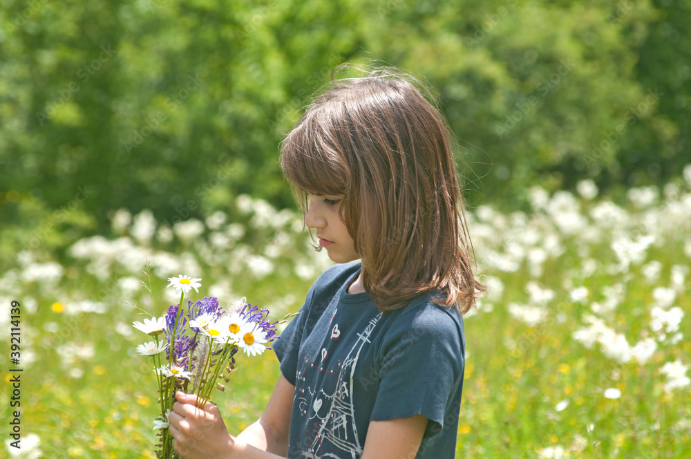 Little girl with field flowers closeup on summer meadow