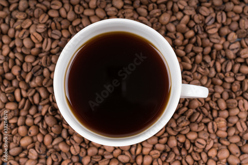 White cup of coffee on beans close-up macro, texture background