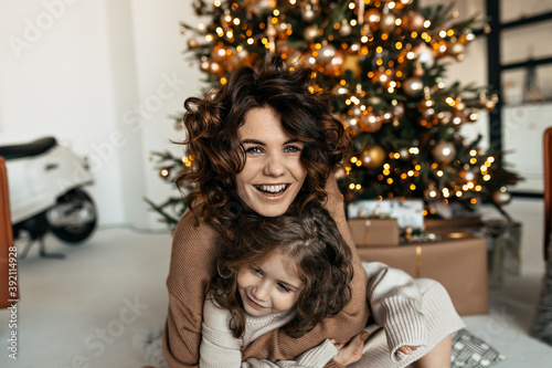 Excited happy woman with little daughter laughing and having fun while celebrating Christmas