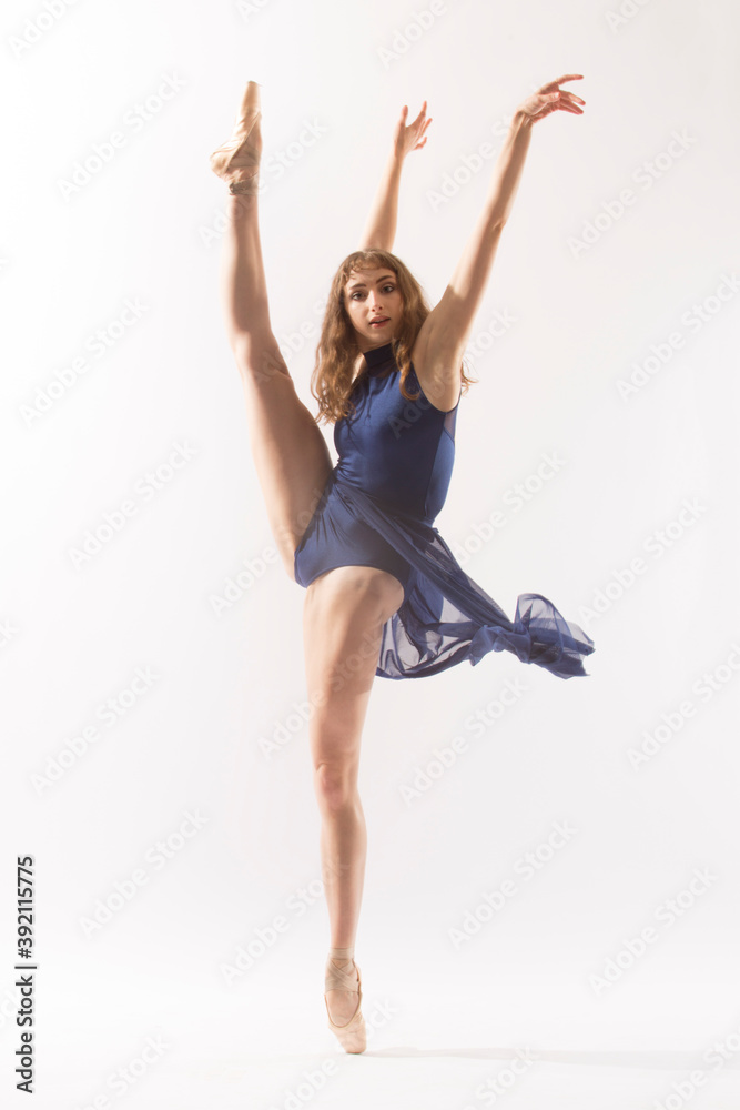 Ballerina in blue skirt with a high kick, white background.