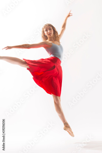 Ballerina in red skirt leaping against a white background.