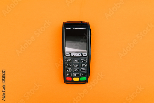 Payment terminal isolated on orange background. A contactless device for paying for purchases with a bank card or smartphone. E-commerce and business