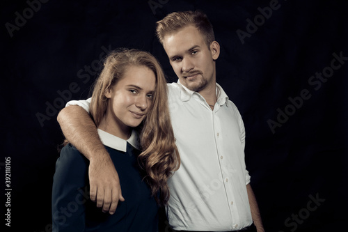 Young beautiful couple studio portrait on black background.