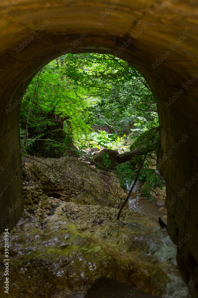 Arch of old stone bridge overthe mountain creek