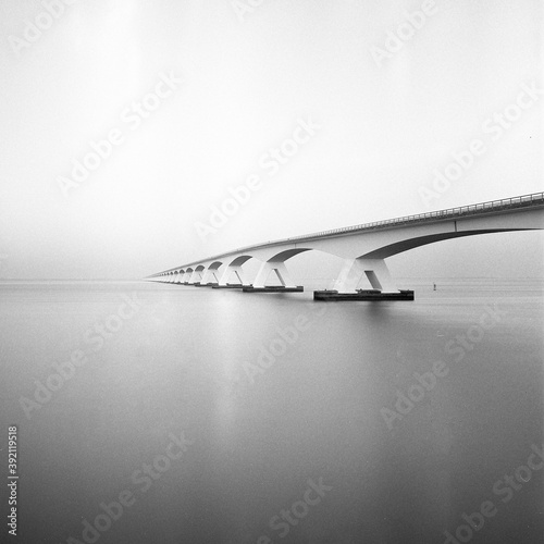 Analog picture in black and white of a long bridge over water