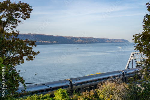 Amtrak train going along Hudson river with a few boats on the water photo