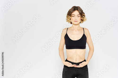 Slender girl in sportswear on a light background leggings hairstyle cropped view