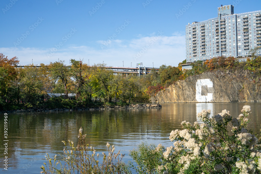 Apartment complex building built on a rock cliff with the letter C, with a view of creek and Inwood Hill Park