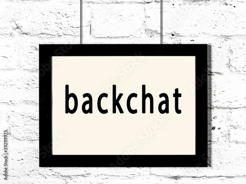 Black frame hanging on white brick wall with inscription backchat