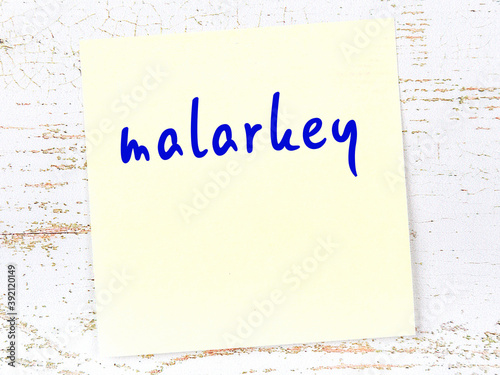 Yellow sticky note on wooden wall with handwritten word malarkey photo