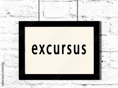Black frame hanging on white brick wall with inscription excursus