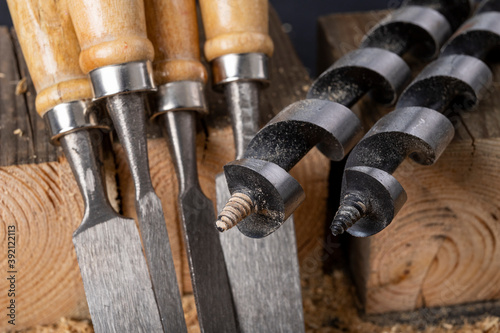 Chisels and wood drills laid on sawdust. Carpentry accessories in the workshop.