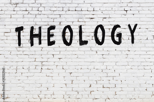 Inscription theology painted on white brick wall